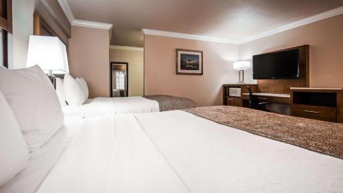 a hotel room with two beds and a flat screen tv at Best Western Bishop Lodge in Bishop