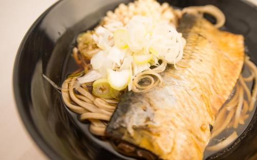 a fish in a bowl with noodles and onions at Guest House COCO in Lake Toya