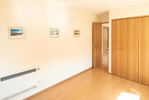Habitación con paredes blancas y puerta de madera. en Guest House COCO, en Lago Toya
