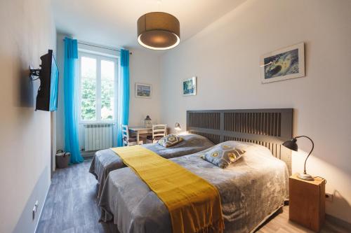 - une chambre dotée d'un lit avec une couverture jaune et grise dans l'établissement les Ormeaux, à Sauternes