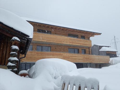 a house covered in snow in front of a building at Haus Riefli- Monique in Sankt Anton am Arlberg