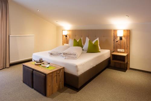 a bedroom with a large bed with green pillows at Alpengasthof Pichler in Sankt Veit in Defereggen