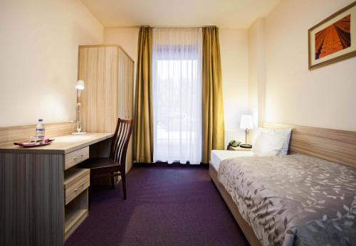 a hotel room with a bed and a desk at Hotel Arsenał in Gliwice