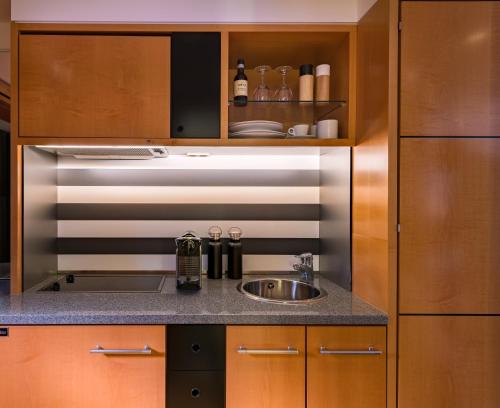 a kitchen with a sink and wooden cabinets at THE MADISON Hotel Hamburg in Hamburg