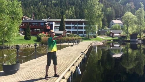a woman standing on a dock holding a fish rod at Revsnes Hotel in Byglandsfjord