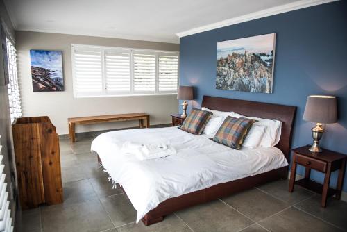 a bedroom with a large bed with blue walls at Villa Vue in Kleinbaai