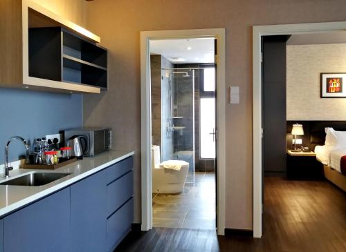 a kitchen with a sink and a room with a bed at The Granite Luxury Hotel Penang in George Town