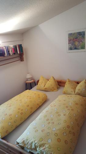 2 łóżka w sypialni z żółtą pościelą i poduszkami w obiekcie Ferienwohnung Angelika w mieście Schruns