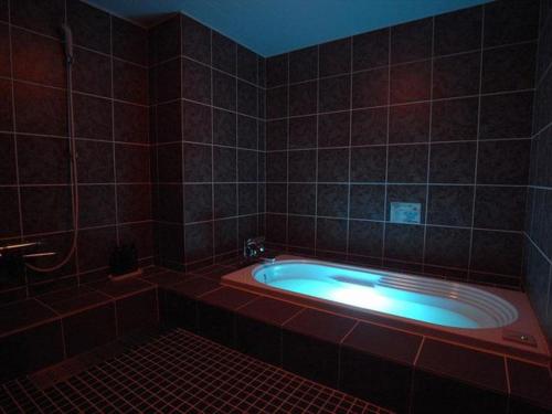 ein Bad mit einer großen Badewanne in einem gefliesten Zimmer in der Unterkunft Hotel Gee (Adult Only) in Sakai
