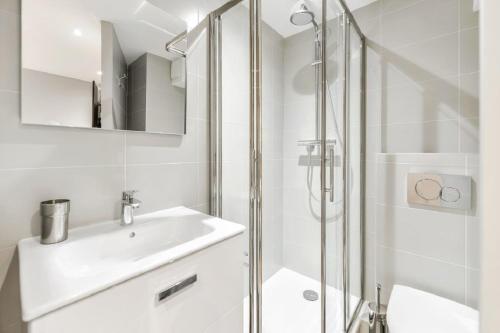 a white bathroom with a sink and a shower at Résidences quartier Charmettoger - maeva Home in Arc 1800