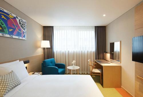 a hotel room with a bed and a chair and a desk at Howard Johnson by Wyndham Incheon Airport in Incheon