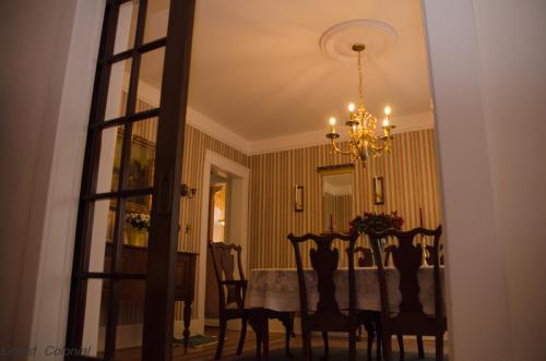 a dining room with a table and chairs and a chandelier at Grand Colonial Bed and Breakfast in Herkimer