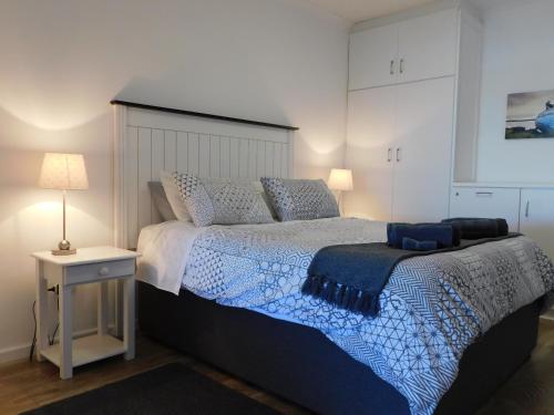 Schlafzimmer mit einem Bett mit einer blauen und weißen Bettdecke in der Unterkunft Rivertides Self Catering Guest House in Velddrif