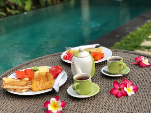 a table with plates of food and two cups of coffee at Ayu Bungalow 2 in Ubud