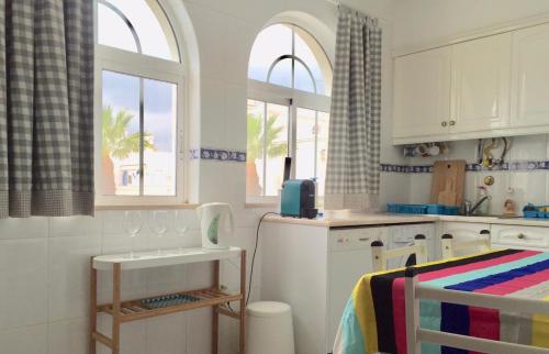 a kitchen with white cabinets and two windows at Tavira Garden- One Bedroom with Terrace in Tavira