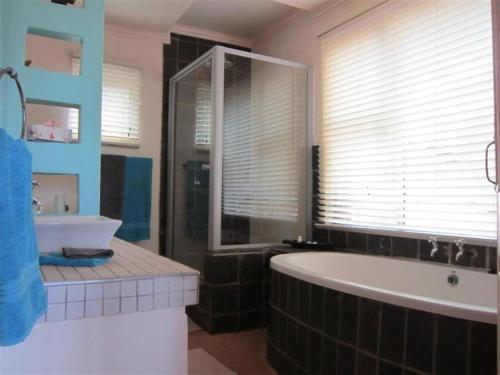 a bathroom with a large tub and a sink at Marula Cottage Guest Lodge in Thabazimbi