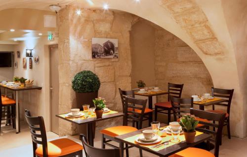 un restaurant avec des tables et des chaises et un mur de pierre dans l'établissement Hôtel 85 Saint Honore, à Paris