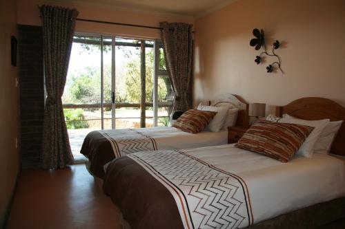 two beds in a hotel room with a window at Marula Cottage Guest Lodge in Thabazimbi