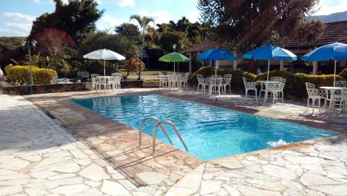 a swimming pool with tables and chairs and umbrellas at Pousada Berço da Liberdade in Tiradentes