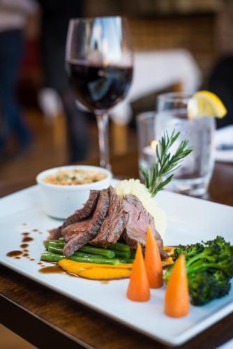a plate of meat and vegetables with a glass of wine at Wild Atlantic Hostel in Leenaun
