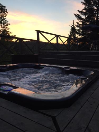 a jacuzzi tub with the sunset in the background at Näkna Hill in Åby