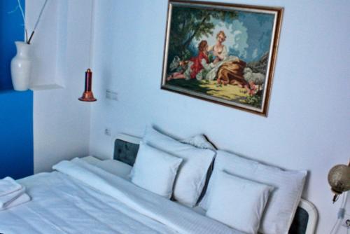 - une chambre avec un lit blanc et une peinture murale dans l'établissement Apartmani15, à Aranđelovac