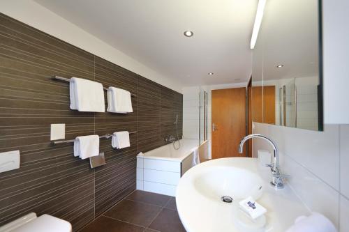 a bathroom with a sink and a tub and a mirror at Hotel Garni Testa Grigia in Zermatt
