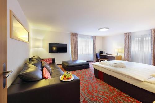 a hotel room with a bed and a couch at Hotel Garni Testa Grigia in Zermatt