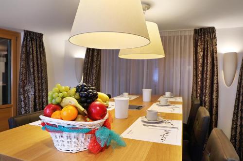 
a table topped with a bowl of fruit and a glass of wine at Hotel Garni Testa Grigia in Zermatt
