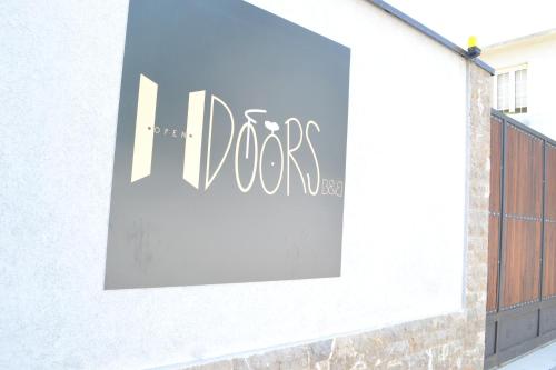 a sign on the side of a building with the word dogs at Open Doors Bed & Breakfast in Shkodër