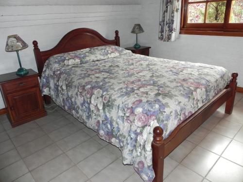 1 dormitorio con 1 cama con colcha de flores y 2 lámparas en Vacances Golf en Pinamar