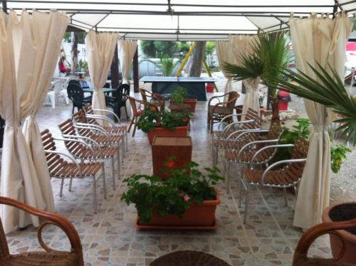 a row of chairs and tables with plants and umbrellas at Residence La Quiete in Taureana