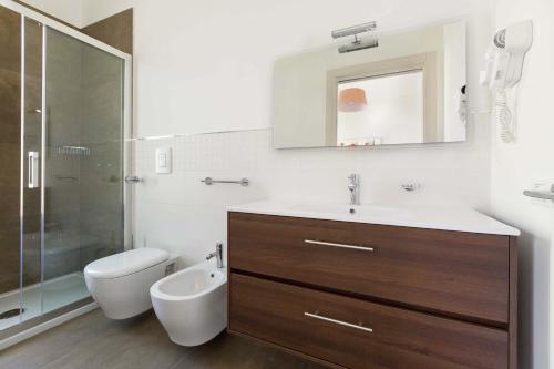 bagno con lavandino, servizi igienici e specchio di Villino Blu Suite by BarbarHouse a Porto Cesareo