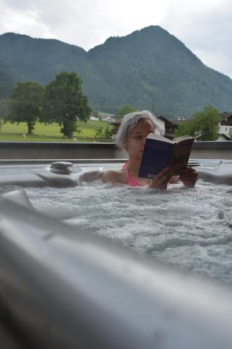 a woman reading a book in a bathtub at Landhaus Greil in Reith im Alpbachtal