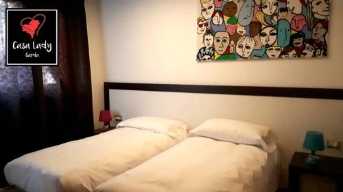 two beds in a bedroom with a painting on the wall at Casa Lady in Garda