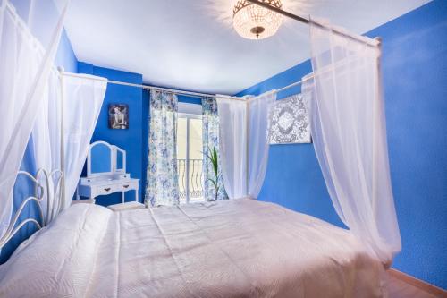 a bedroom with blue walls and a bed with a canopy at Stylish Apartment in Villajoyosa