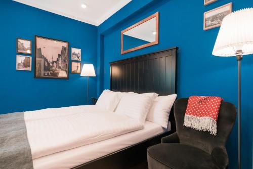 a blue bedroom with a bed and a chair at Revelton Studios Františkovy Lázně in Františkovy Lázně