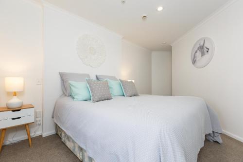 um quarto branco com uma cama e uma mesa de cabeceira em Stylish and Spacious, Downtown Mount Maunganui em Mount Maunganui