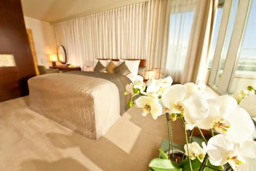 a bedroom with a bed with white flowers in the foreground at Dorint Hotel am Heumarkt Köln in Cologne