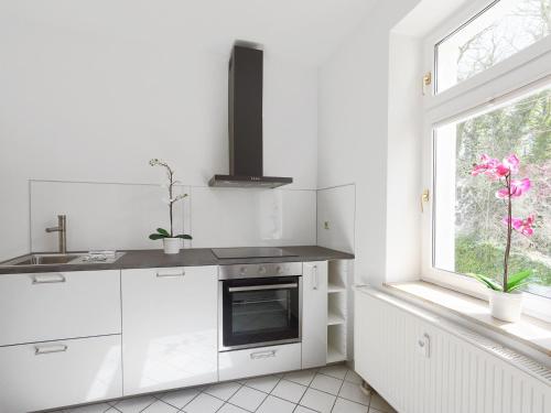 eine weiße Küche mit einem Waschbecken und einem Fenster in der Unterkunft City Park Apartments - #1-8 - Stilvolle Apartments zentrumsnah in Leipzig