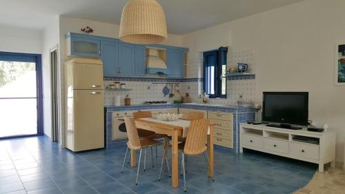 cocina con armarios azules, mesa y TV en Casa Vacanze MARESOLE, en Mattinata