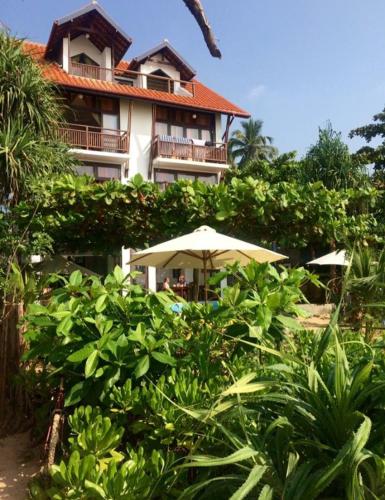a building with an umbrella in front of it at Talalla Bay Beach in Talalla