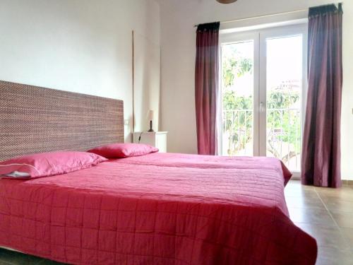 una camera da letto con un letto rosso e una grande finestra di Casa Magnani sardegna a Mògoro