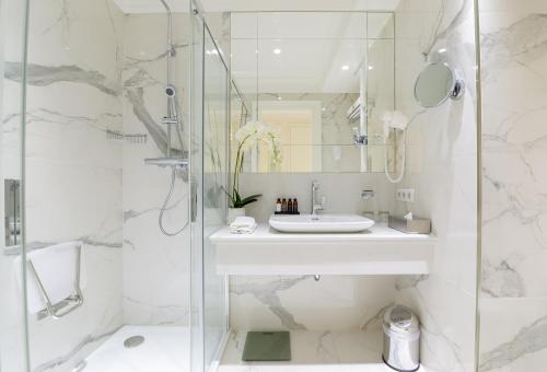 a white bathroom with a sink and a shower at Boutique Hotel Corso in Karlovy Vary