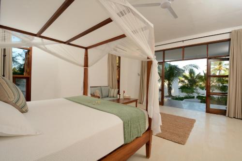1 dormitorio con 1 cama blanca con dosel en Kisiwa on the Beach, en Paje