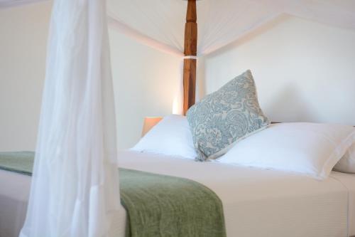 
a bed with a white bedspread and pillows at Kisiwa on the Beach in Paje
