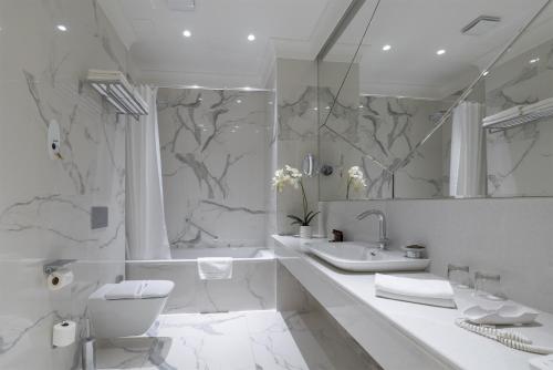 a white bathroom with a toilet and a sink at Boutique Hotel Corso in Karlovy Vary