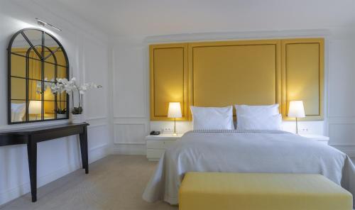 a bedroom with a bed with a yellow headboard and a desk at Boutique Hotel Corso in Karlovy Vary