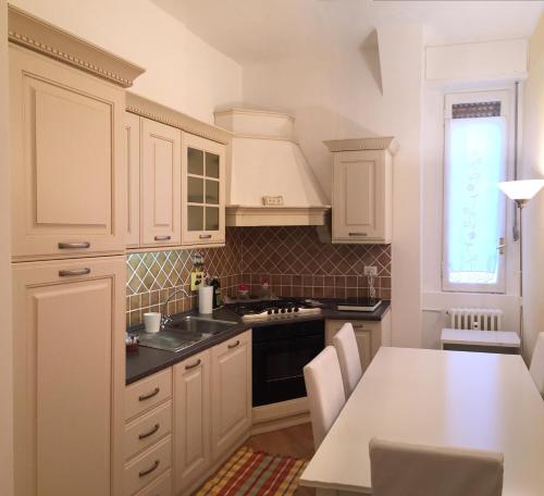 une cuisine avec des placards blancs et une table avec des chaises dans l'établissement 3 Via Guglielmo Koerner Apartment, à Milan