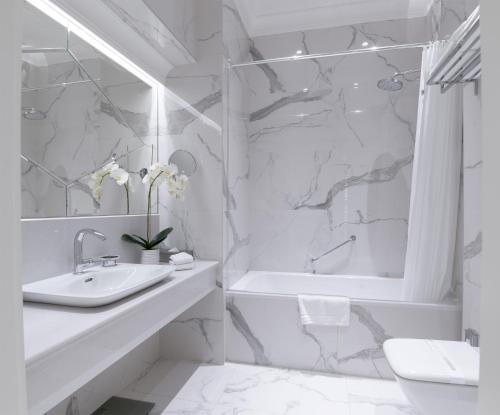 a white bathroom with a sink and a tub and a shower at Boutique Hotel Corso in Karlovy Vary